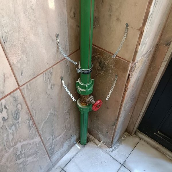 Tubería verde vertical con una llave de paso en una esquina