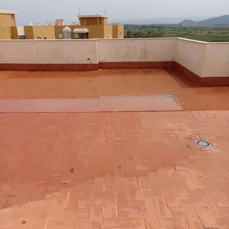 Terraza de color terracota de un edificio con una zono impermeabilizada y brillante